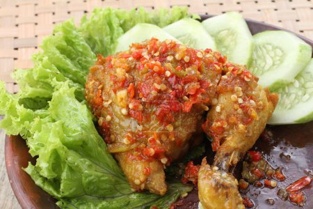 Téléchargez les photos : Ayam penyet  is Indonesian fried chicken dish consisting of fried chicken that is smashed with the pestle against mortar to make it softer, served with sambal, slices of cucumbers, fried tofu and tempeh. - en image libre de droit