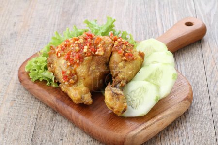 Foto de Ayam penyet  is Indonesian fried chicken dish consisting of fried chicken that is smashed with the pestle against mortar to make it softer, served with sambal, slices of cucumbers, fried tofu and tempeh. - Imagen libre de derechos