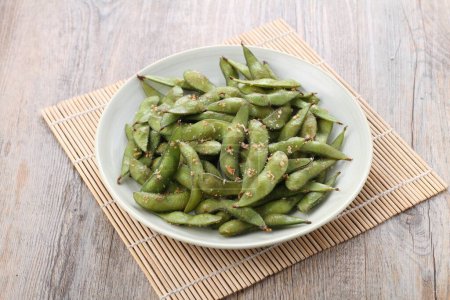 Téléchargez les photos : Edamame is Japanese dish and prepared of immature soybeans in the pod. The pods are boiled or steamed and may be served with salt or other condiments. Nowadays it became to be so popular in the world - en image libre de droit