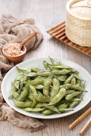 Photo for Edamame is Japanese dish and prepared of immature soybeans in the pod. The pods are boiled or steamed and may be served with salt or other condiments. Nowadays it became to be so popular in the world - Royalty Free Image
