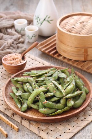 Téléchargez les photos : Edamame is Japanese dish and prepared of immature soybeans in the pod. The pods are boiled or steamed and may be served with salt or other condiments. Nowadays it became to be so popular in the world - en image libre de droit