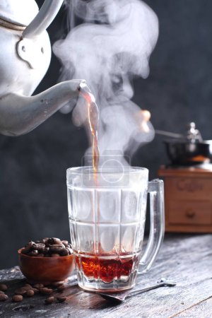 Foto de Kopi Tubruk es un café de estilo indonesio donde se vierte agua caliente sobre finos granos de café directamente en el vaso, sin ninguna filtración, por lo general con azúcar añadido. En Bali, Kopi Tubruk es conocido por el nombre "Kopi Selem", que significa café negro.. - Imagen libre de derechos