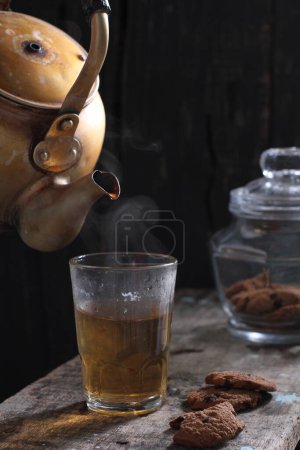 Photo for Tea is an aromatic beverage prepared by pouring hot or boiling water over cured or fresh leaves of Camellia sinensis, an evergreen shrub native to East Asia which probably originated in the borderlands of southwestern China and northern Myanmar. - Royalty Free Image