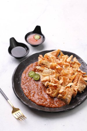 Photo for Batagor is a Sundanese dish from Indonesia, and popular in Southeast Asia, consisting of fried fish dumplings, usually served with peanut sauce. It is traditionally made from minced tenggiri - Royalty Free Image
