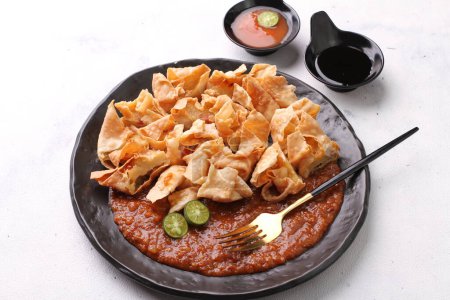 Photo for Batagor is a Sundanese dish from Indonesia, and popular in Southeast Asia, consisting of fried fish dumplings, usually served with peanut sauce. It is traditionally made from minced tenggiri - Royalty Free Image
