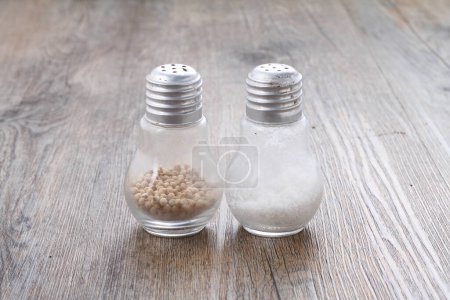 Photo for Salt shaker and pepper on a white wooden desk - Royalty Free Image