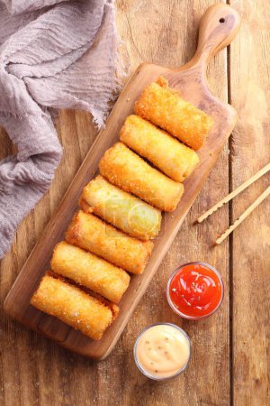 Photo for Fried fish sticks in a pan and sauce with sesame on a wooden board. - Royalty Free Image