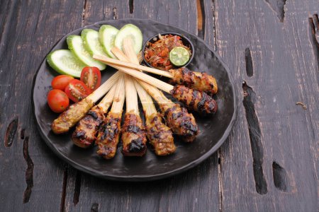 Photo for Sate lilit is a satay variant in Indonesia, originating from Balinese cuisine. This satay is made from minced pork, fish, chicken, beef, or even turtle meat, which is then mixed with grated coconut - Royalty Free Image