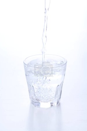 Photo for Pouring water into glass on white background - Royalty Free Image