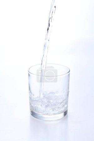 Téléchargez les photos : Un verre avec une bouteille et une tasse d'eau isolée sur un fond blanc - en image libre de droit