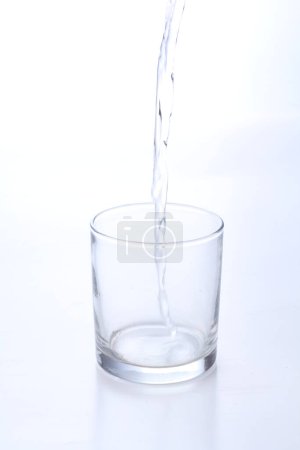 Foto de Un agua que vierte en un vaso con un fondo blanco - Imagen libre de derechos