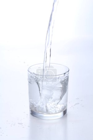 Foto de Verter agua en vidrio con burbujas aisladas sobre fondo blanco - Imagen libre de derechos