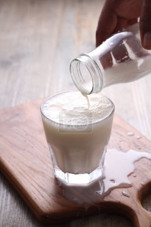 Téléchargez les photos : Verre de lait avec une paille sur fond en bois - en image libre de droit