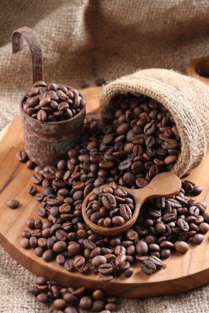 Photo for Coffee beans in a wooden bowl on a burlap bag. top view, close up, selective focus, - Royalty Free Image