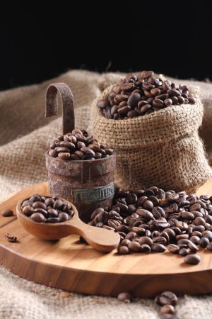 Foto de Granos de café tostados, cuchara de madera con taza de espresso, saco y madera - Imagen libre de derechos