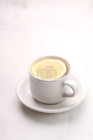 Téléchargez les photos : Tasse de citron avec menthe fraîche dans un bol en porcelaine blanche sur fond clair. espace pour le texte. - en image libre de droit