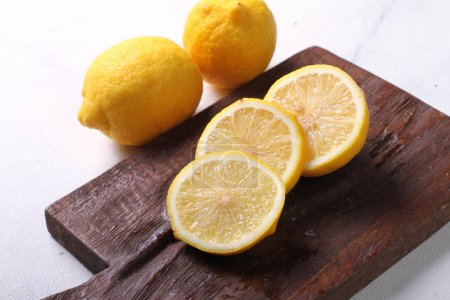 Téléchargez les photos : Tranches de citron sur planche de bois sur fond blanc - en image libre de droit