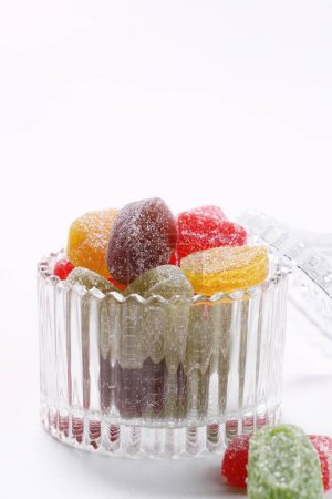Foto de Caramelos de jalea de colores en cuenco de vidrio sobre fondo blanco - Imagen libre de derechos