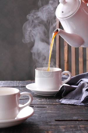 Foto de Taza de té con un humo blanco en una mesa de madera - Imagen libre de derechos