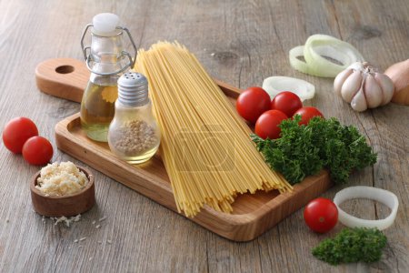 Téléchargez les photos : Ingrédients pour la cuisson des pâtes, tomates, ail, poivre, huile d'olive et basilic sur fond de bois - en image libre de droit