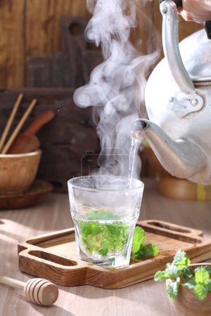 Téléchargez les photos : Tasse avec thé et théière sur table en bois - en image libre de droit