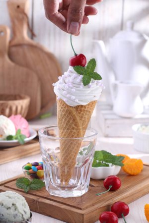 Photo for A person scooping a cherry into a cone of ice cream - Royalty Free Image