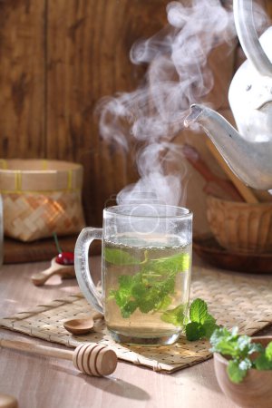 Téléchargez les photos : Tasse avec thé et théière sur une table en bois - en image libre de droit