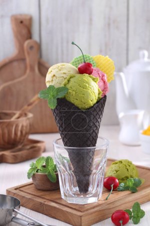 Foto de Delicioso helado en cono de gofre y taza con chocolate - Imagen libre de derechos
