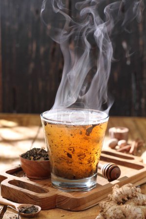 Foto de Té caliente en una taza de vidrio con vapor caliente en la mesa de madera - Imagen libre de derechos