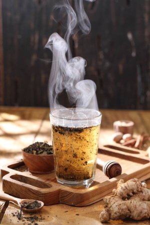 Foto de Taza de bebida caliente con palitos de canela y hojas de menta en la mesa de madera - Imagen libre de derechos