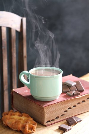 Foto de Taza de chocolate caliente con canela, galletas y chocolate sobre fondo de madera - Imagen libre de derechos