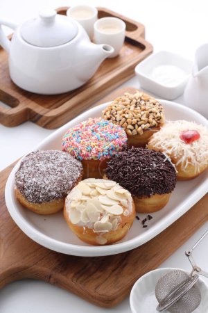 Téléchargez les photos : Une tasse de café avec des beignets et des bonbons sur une table en bois blanc. - en image libre de droit