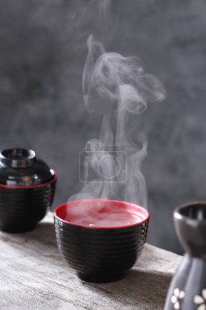 Téléchargez les photos : Thé noir avec une tasse de thé noir sur fond noir - en image libre de droit