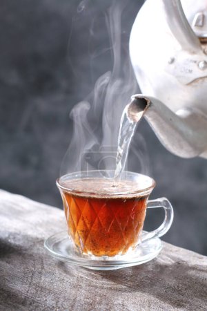 Photo for Cup of tea with steam and cinnamon stick - Royalty Free Image