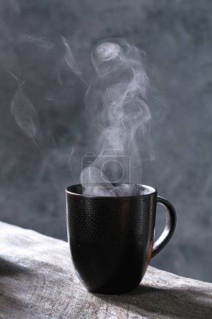 Téléchargez les photos : Tasse de café chaud avec de la vapeur sur fond sombre - en image libre de droit