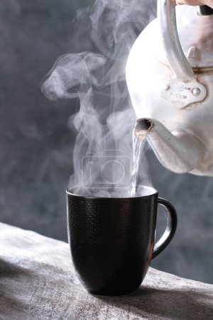 Foto de Café caliente en taza con cuchara sobre mesa negra, primer plano - Imagen libre de derechos