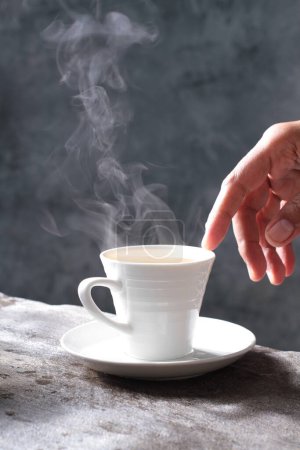 Téléchargez les photos : Femme tenant une tasse de café à la vapeur sur fond de table sombre - en image libre de droit