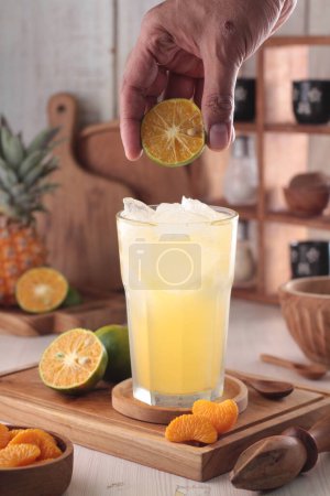 Foto de Vaso de sabroso jugo de naranja con hielo y limón sobre la mesa - Imagen libre de derechos