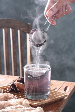 Téléchargez les photos : Un homme verse du thé chaud dans une théière en verre sur le fond de la fumée - en image libre de droit