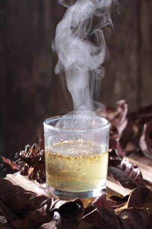 Photo for A vertical shot of a cup of tea and a glass of whisky on a wooden table - Royalty Free Image