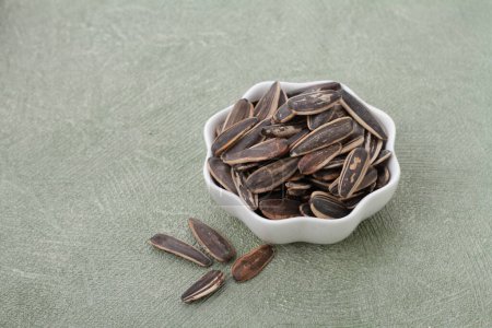Foto de Tazón y tazón con sabrosas semillas de calabaza sobre fondo gris - Imagen libre de derechos