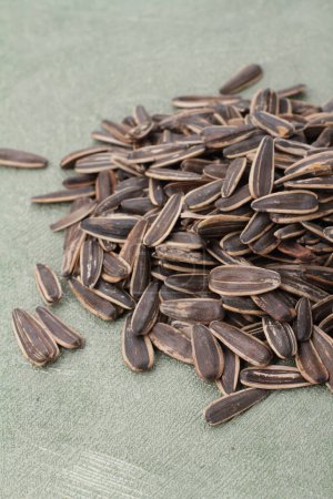 Photo for Heap of black sunflower seeds on a light wooden background. - Royalty Free Image