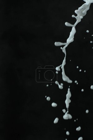 Téléchargez les photos : Peinture blanche éclaboussure isolée sur fond noir - en image libre de droit
