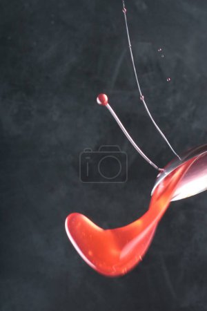 Foto de Salpicadura de líquido rojo en forma de una gota de líquido. macrofotografía de líquido. - Imagen libre de derechos