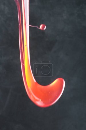 Foto de Gota roja con gota de agua sobre fondo negro - Imagen libre de derechos