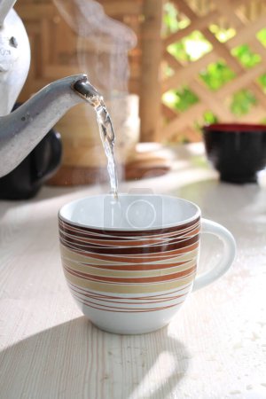 Téléchargez les photos : Une tasse de thé chaud et une théière sur une table en bois - en image libre de droit