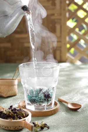 Téléchargez les photos : Thé vert dans un bol en verre sur une table en bois avec des feuilles de thé - en image libre de droit