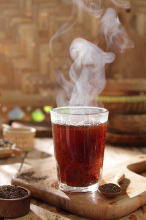 Téléchargez les photos : Thé sur fond bois, fumée dans une tasse en verre - en image libre de droit