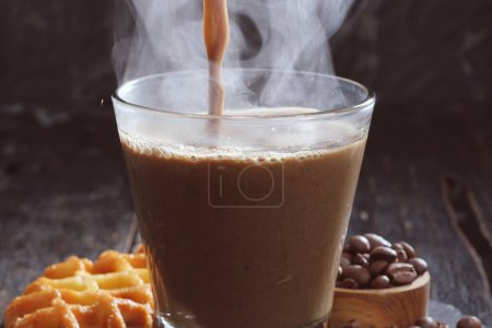 Foto de Vaso de sabroso café con leche y granos de café en la mesa oscura - Imagen libre de derechos