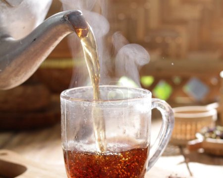 Téléchargez les photos : Thé chaud dans la tasse en verre sur une table en bois - en image libre de droit